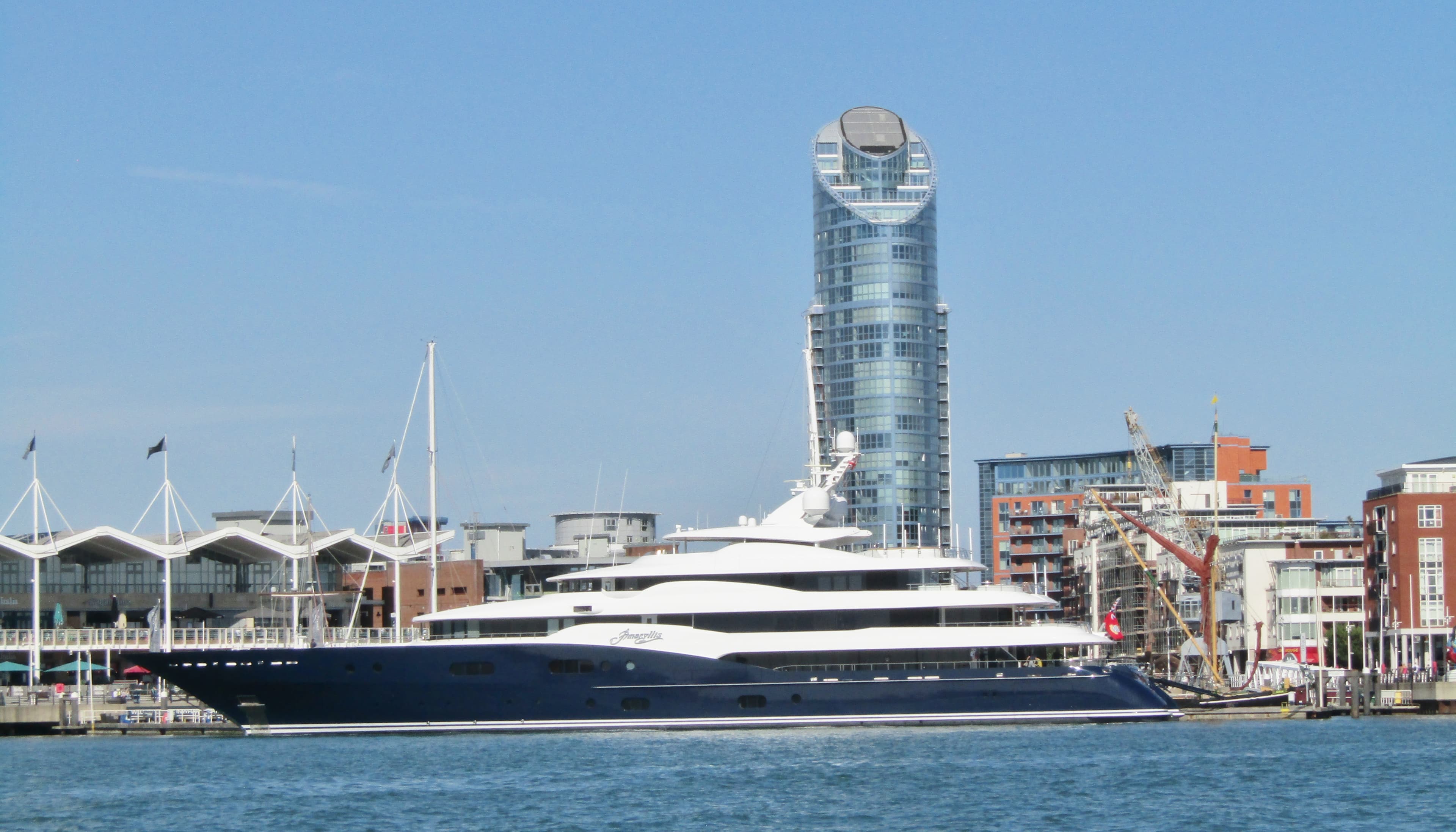 A superyacht alongside at Gunwharf Quays, Portsmouth, with the Spinnaker Tower beyond